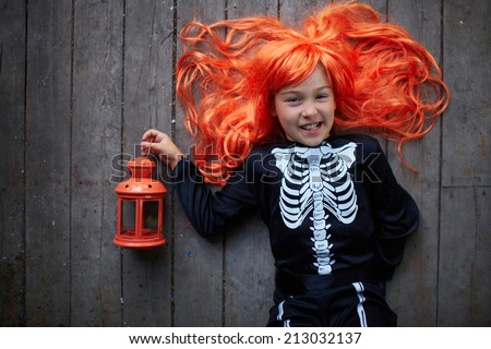 Portrait of cute girl in red wig holding lantern