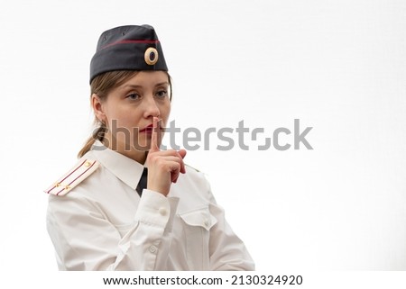 Beautiful young female Russian police officer in dress uniform shows signs with her hands on a white background. Selective focus. Portrait