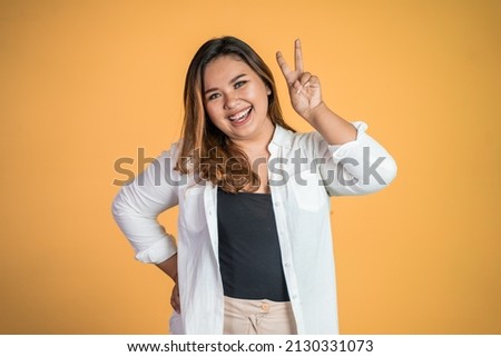 asian woman with cute hand gesture making v shape on finger Royalty-Free Stock Photo #2130331073