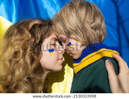 faces of boy child and young woman with painted yellow - blue heart on cheeks. Family, unity, support. Ukrainians are against war. request for help to world community.Caring for each other Royalty-Free Stock Photo #2130333908