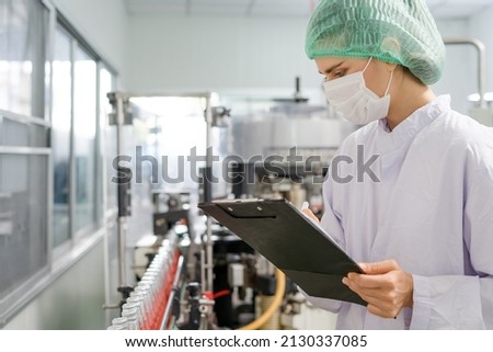 Quality control engineers work in the production and bottling facility for fruit juice or medicine. Staff inspect the quality of food and drugs before delivery to customers. Royalty-Free Stock Photo #2130337085