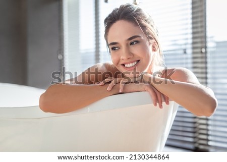 Home Spa. Portrait Of Smiling Young Female Resting In Bathtub, Beautiful Millennial Woman Relaxing In Modern Bathroom Interior, Happy Lady Enjoying Taking Hot Bath, Closeup Shot With Free Space