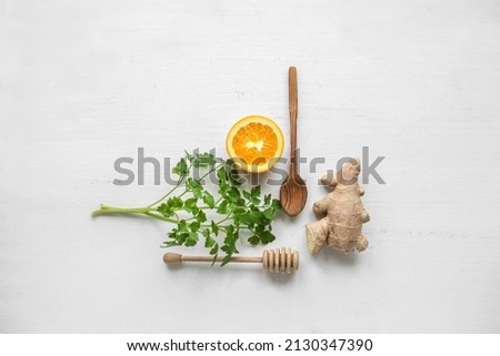 ginger, orange, parsley and wood spoons on white table. product photography flat lay