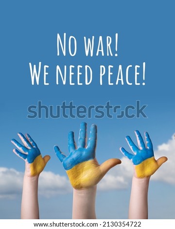 Child's hands painted in the colors of the national flag of Ukraine on blue sky background. Text - No war We nees peace Royalty-Free Stock Photo #2130354722