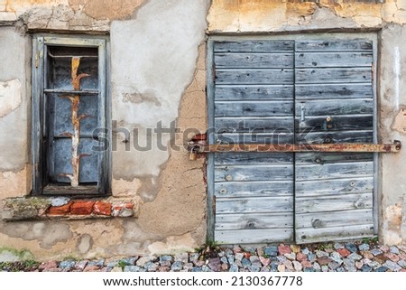 Historic stone house with old locked wooden doors and window with bars. Kuldiga, Latvia.