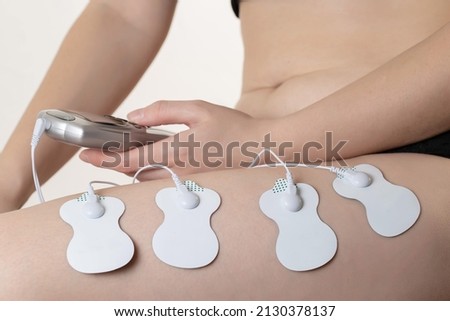 Electrodes of modern acupuncture and anti-cellulite massagers on the legs of a girl in problem areas. Home physiotherapy Royalty-Free Stock Photo #2130378137