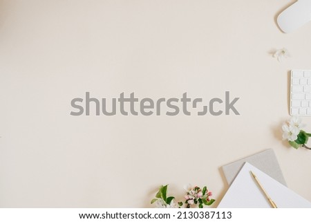 Female blog composition with notebook, pen, computer and white apple flowers on beige background. Flat lay, top view, copy space