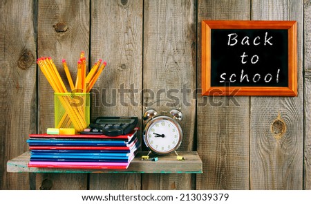Back to school. Writing-books and school tools on a wooden shelf.