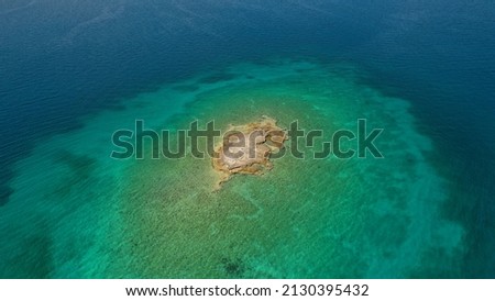Aerial drone photo of small paradise tropical island and sandy beach forming an emerald clear sea lagoon