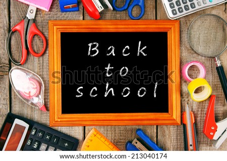 Back to school. Frame and school tools. Vertically. A wooden background.