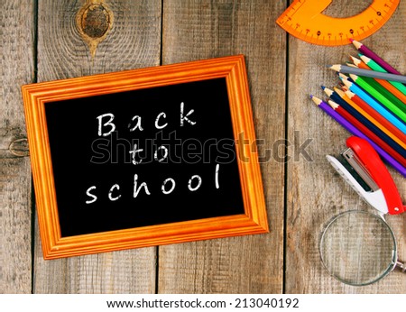 Back to school. Frame and school tools. Vertically. A wooden background.
