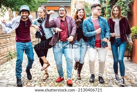 Happy urban friends walking at old town acting crazy funny moves - Young guys and girls having fun on city street with party travel mood - College students at university campus on bright vivid filter Royalty-Free Stock Photo #2130406721
