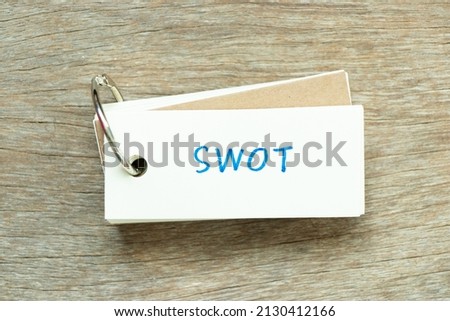 Flash card with handwriting word SWOT (abbreviation of strength, weakness, opportunities, threats) on wood background