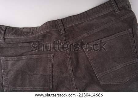 The back of dark corduroy trousers. Pockets are visible. Close