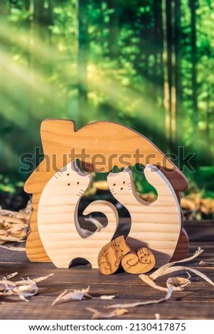 Wooden puzzle in the form of a handmade cat family on the background of the forest.