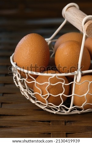 eggs in a white wire basket on a bamboo table. food photography.