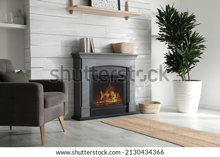 Cozy living room interior with comfortable armchair and modern electric fireplace Royalty-Free Stock Photo #2130434366