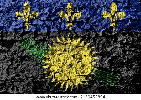 Guadeloupe flag depicted on a stone wall. The texture of the stone blends perfectly with the colors of the banner