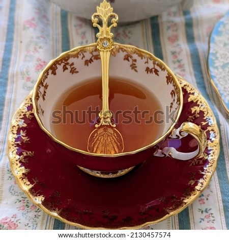 Black tea served in fine English bone china teacup and saucer with gold spoo Royalty-Free Stock Photo #2130457574