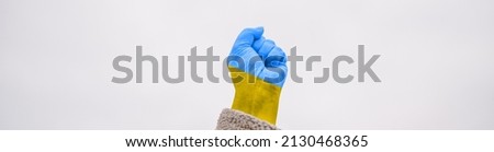 International political relationship between Ukraine and Russia. female hand fist painted in Ukraine flag colors yellow-blue against blue sky