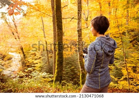 Woman trekking in the forest and taking pictures with dlsr camera