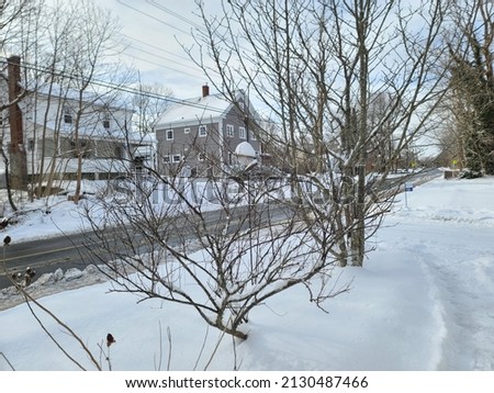 A snow filled area along a suburban street. The road is plowed and the driveway got reaccumulated.
