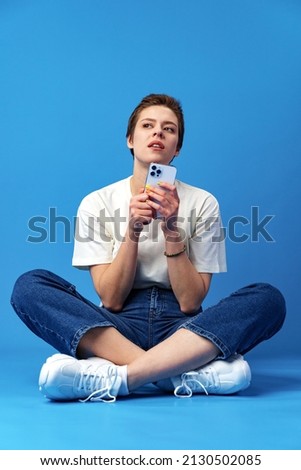 Happy nice girl using cellphone isolated over blue background
