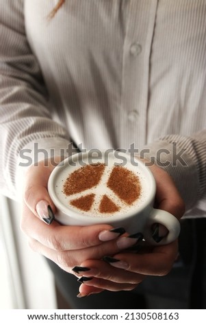 Coffee with peace sign from cinnamon in a hand of a waitress.