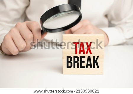Cropped view of hands holding wooden cube with TAX Break lettering on work table. Top view
