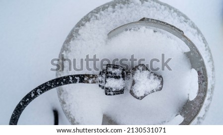 Abstract geometry of snow-covered gas tank and hose