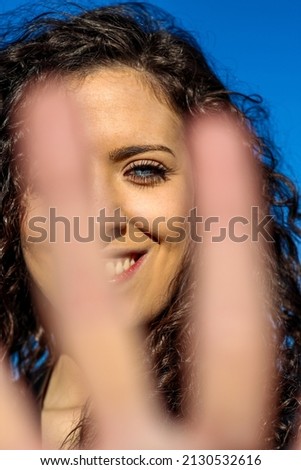 vertical close up of Portrait of a smiling blue-eyed young woman showing a stop sign while standing outdoors.