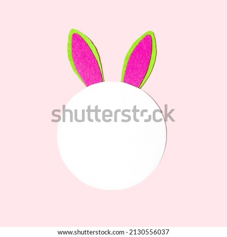 Flat lay, on a soft pink background, bunny ears next to copy space for text.  Holiday concept light happy easter, children's creativity.  Close-up.  Top view, foreground.
