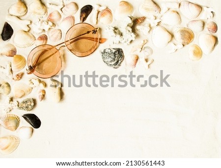 Flat lay.  Sunglasses, seashells, corals and pebbles lie on the sea sand.  The concept of vacation, travel.  Space for copy text.  Horizontal layout.  Close-up, background image.