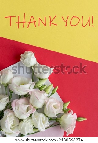 Eustoma flowers with envelope and sheet of paper on colorful background. thank you text on yellow. vertical image