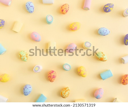 Pastel Easter eggs pattern with marshmallow candies  on a sunny yellow background. Minimal creative concept of Easter.