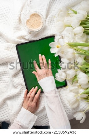 green screen tablet, young woman looking for mother's day gift online, tulips 