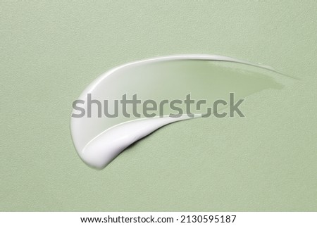 White cosmetic cream texture, skincare lotion swatch on green. Face creme, body moisturiser, hair conditioner smear smudge stroke on color background. Creamy beauty product closeup Royalty-Free Stock Photo #2130595187