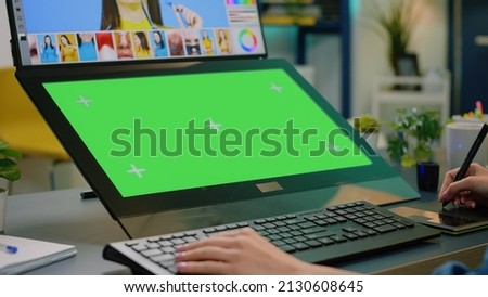 Close up of horizontal green screen at editing workplace. Woman photographer looking at chroma key with mockup template and isolated background, retouching pictures on computer app