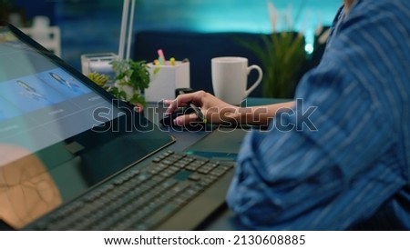 Close up of photographer hands using graphic tablet and stylus while retouching pictures in photography studio. Artist doing retouch work with editing software on computer and equipment