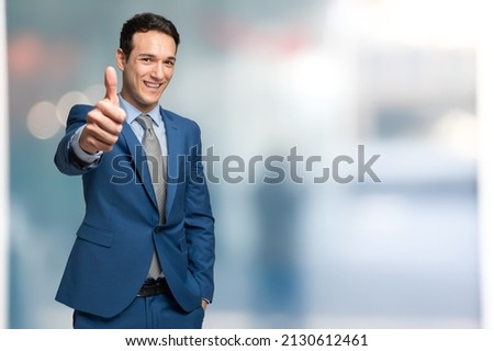 Businessman doing thumbs up sign, bright background