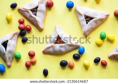 Hamantashen - traditional cookies for Jewish holiday Purim. Triangle cookies with assorted fillings on a yellow background.