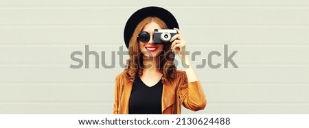 Portrait of happy smiling young woman photographer with film camera on gray background