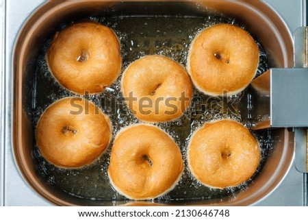 Donuts frying in deep fat. Preparation of traditional donuts, six round donuts in boiling oil. Royalty-Free Stock Photo #2130646748