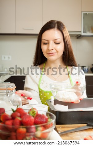 Beautiful young woman preparing strawberry cake