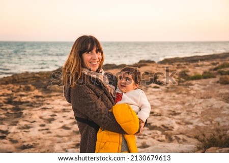 Lifestyle of a family on the beach, a mother hugging her baby by the sea