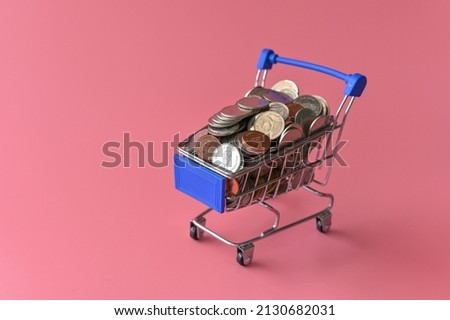 Many coins in the blue shopping cart Isolated on pink background and copy space, saving and investment concept.