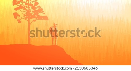 A tourist with a backpack on a rock meets dawn. Mountains covered by forest, taiga. Morning haze, the light of sunrise.