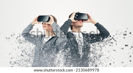 Pixelated shot of man and woman exploring virtual reality and immersing into cyberspace on white background in studio