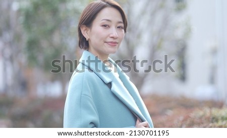A smiling Japanese woman in a coat