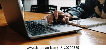 Cropped photo of asian woman using laptop and writing making list taking notes in notepad working or learning on laptop indoors- educational course or training, seminar, education online concept
